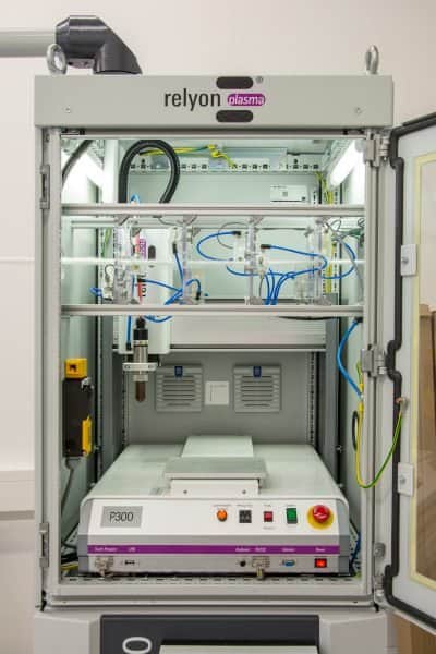 Process chamber with the jet of Plasmabrush® PB3 in the background and the passage of a textile fibre through the Piezo Radial Source in the upper part